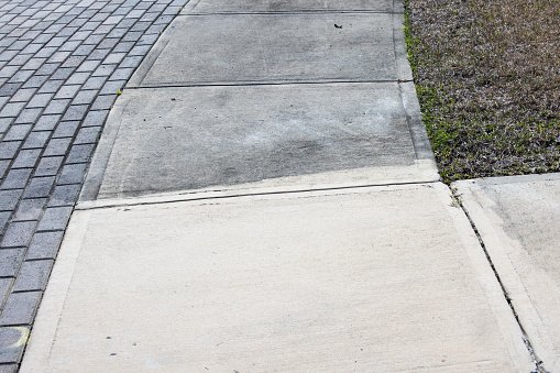 Patrially cleaned and partial irty cement sidewalk in front of a homeafter some of it has been pressure washed and some has not.