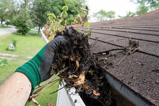 Worker cleaning gutters for a customer.