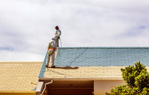 Cape Town, South Africa - November, 4th 2015: Two men painting a roof of a house, spray painting wearing protective clothing and masks in a housing complex of Woodbridge, Cape Town.